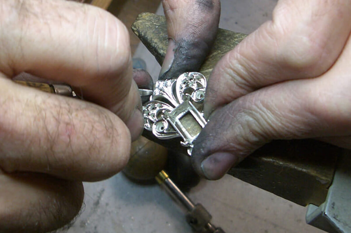 hands working on silver pendant